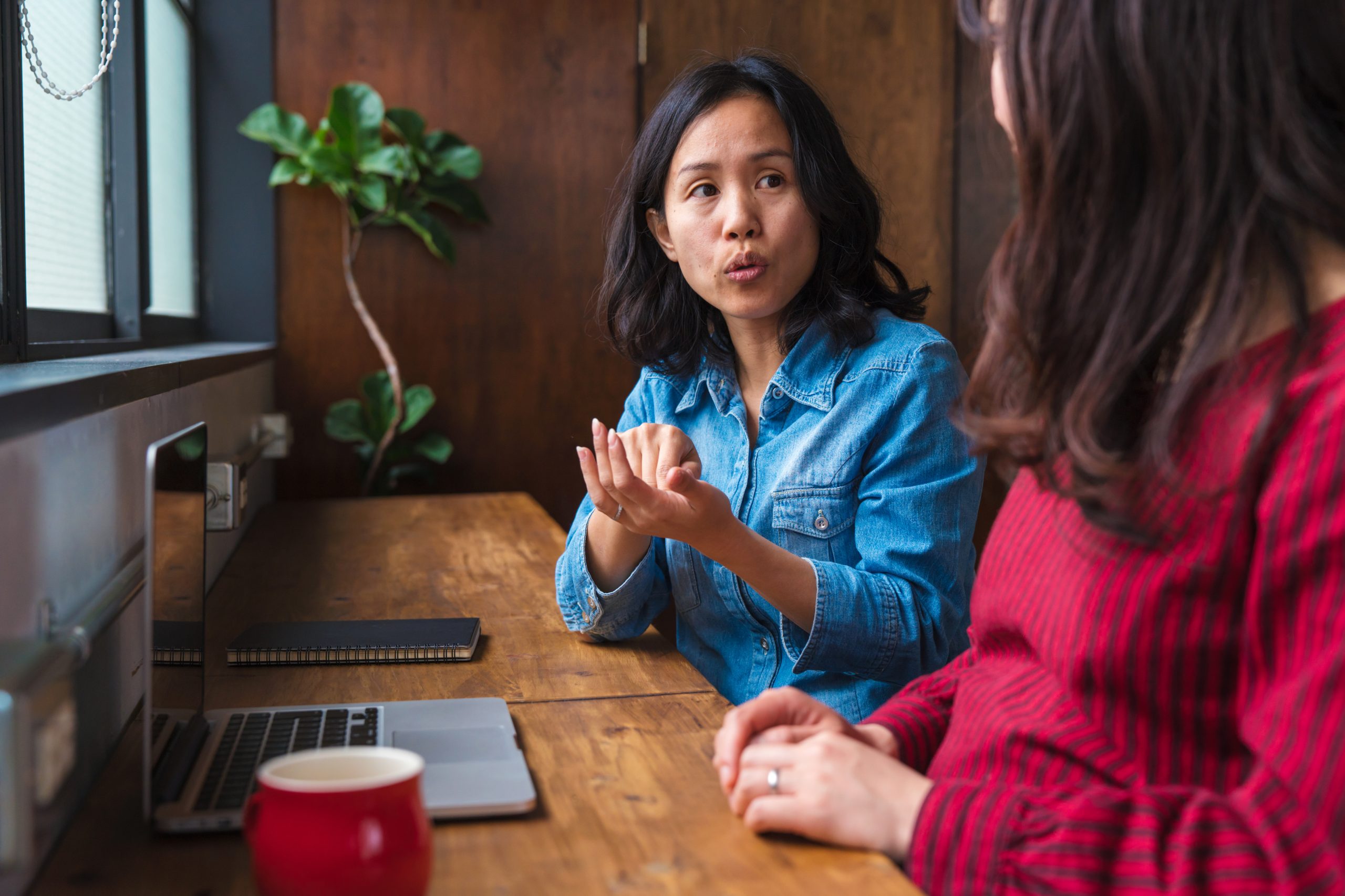 Two young adult women in an office talking